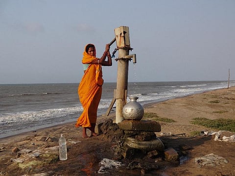 A woman collecting  groundwater from the sea erosion hit Satabhaya village in Odisha. File photo: Ashis Senapati