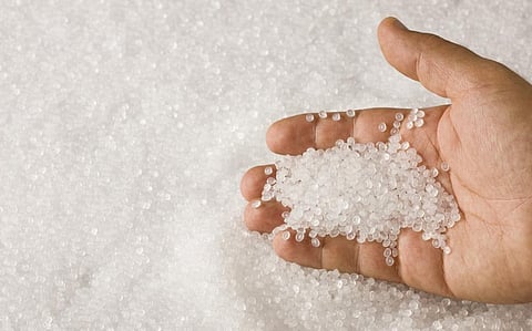 A hand sifting through a pile of clear plastic resin pellets. Photo: iStock