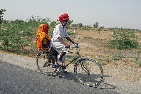 साइकिल की मदद से अपनी मंजिल की ओर जाती भारतीय किसान दंपत्ति; फोटो: आईस्टॉक