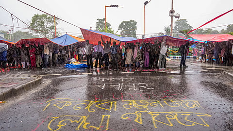 Agitators take cover during rains during sit-in demonstration against the RG Kar Hospital incident, outside Swasthya Bhavan in Kolkata, Friday, Sept. 13, 2024
