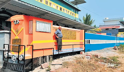 The house of T Damodaran modelled after a train coach. The wall is in the shape of a rake hauled by an orange liveried ALCO locomotive
