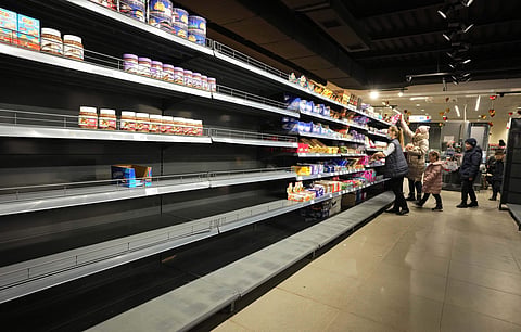 People walk next to nearly empty shelves at a shop in Nikolaev, Ukraine, Tuesday (Pic: AP)