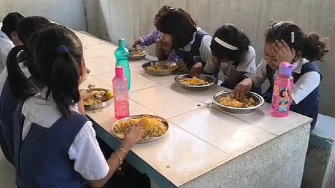 স্কুলের পোশাক পরা পড়ুয়া খাবার খাচ্ছে