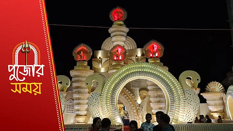 রাতে আলোকসজ্জায় উজ্জ্বল রাজহাঁসের আদলে নির্মিত কাল্পনিক কালচারাল পূজা মণ্ডপ এবং সামনে দর্শকদের ভিড়।