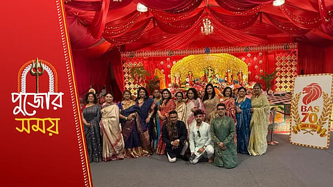 মা দুর্গার প্রতিমার সামনে বেশ কয়েকজন ব্যক্তি দাঁড়িয়ে আছে 