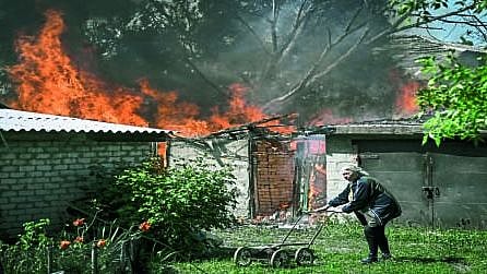 घराच्या मागेच बाँब फुटून आग लागल्यानंतर घरापासून दूर जाताना महिला.
