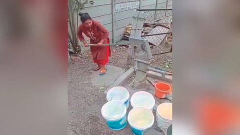 बोअरवेल आटली असली तरी त्यातून पाणी काढण्याचा प्रयत्न करताना महिला. 