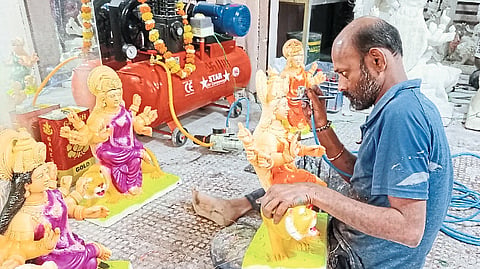 An artisan engaged in the work of making an idol of a goddess.