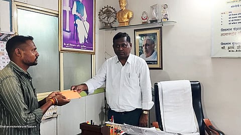 Principal I D. Patel. while handing over financial aid for child's education to Ritesh Dodve. 