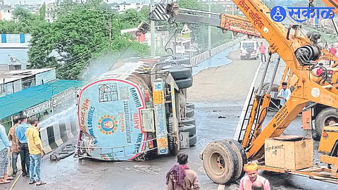 Workers splashing water on an overturned diesel tanker on a flyover on the Mumbai-Agra highway

