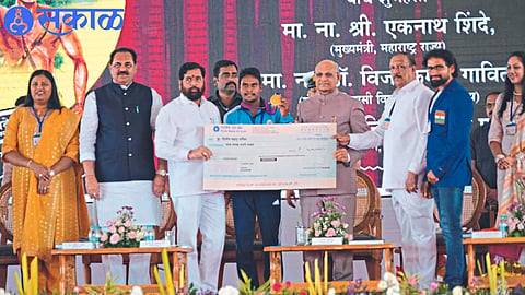 Rajyaral Ramesh Bais giving a check of Rs 5 lakhs to Dilip Gavit, a disabled tribal athlete. Neighboring Chief Minister Eknath Shinde,