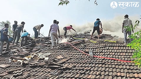 Firefighters and villagers extinguishing the fire at the house of farmer Dada Sable.