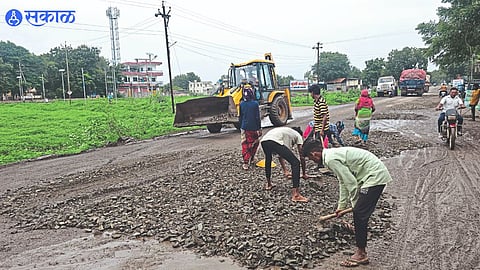 Laborers filling potholes on Khetiya road in Shahada town.