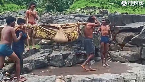 Villagers crossing the river carrying a bamboo bag to a pregnant woman from the flood water.