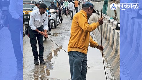 hinjewadi Traffic warden clearing a drain to allow stagnant water to flow away.