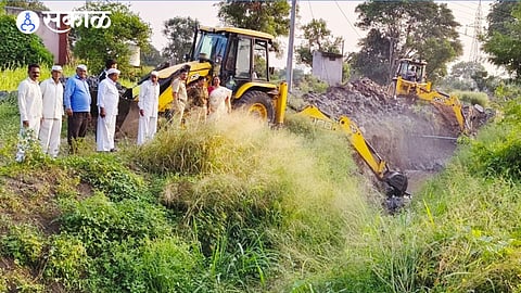 Administration officials, police and villagers remove encroachments in the Awasari Khurd stream using a JCB machine