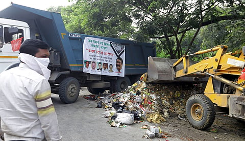 ट्रकमध्ये कचरा टाकताना कार्यकर्ता. 