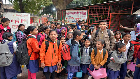 थंडीपासून बचावासाठी शाळकरी विद्यार्थी उबदार कपडे परिधान करत आहेत.