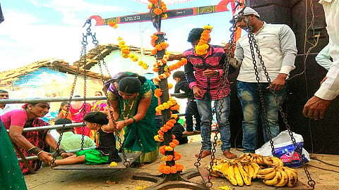 किन्हवली : नवसाने पूत्रप्राप्ती झालेल्या महिला आपल्या बाळाला वजन काट्यात त्याच्या वजना इतक्‍या फळांनी जोखतात.