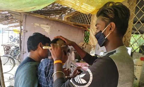 गडचिरोली : केशकर्तनालयात बालकाचे टक्‍कल करताना कारागीर.