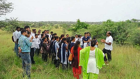 लामकानी (ता. धुळे) - नैसर्गिक पुनरुज्जीवनातून बहरलेल्या माळरानावर जैवविविधतेच्या अभ्यासासाठी आलेल्या पुण्यातील इकॉलॉजी सोसायटीच्या सदस्यांशी संवाद साधताना डॉ. धनंजय नेवाडकर.