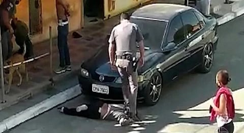 Police stand with their feet on the neck of a black woman in brazil