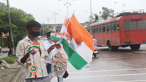 ग्राहकाच्या प्रतीक्षेत रस्त्यावर उभा असलेला झेंडा विक्रेता