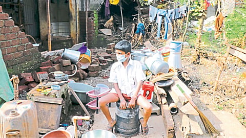 कोल्हापूर - पुराची झळ बसलेल्या घरातील साहित्याकडे हताशपणे पाहणारा मुलगा.