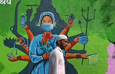 The first two waves of the Covid-19 pandemic possibly claimed four million lives in India. Still, the question of healthcare remains absent from national politics.

A man walks past a mural showing a health worker and a shadow of a Hindu deity, painted to create awareness about the spread of Covid-19 in Mumbai. November 2021. Photo: ZUMA Wire / IMAGO