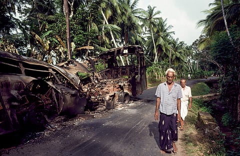 Civilians walk past a burnt-out bus in southern Sri Lanka in 1989, during the second JVP insurrection. The shock of the first, in 1971, turned the world of Sri Lankan letters towards the political, and invited the country’s anglophone elite to an unsparing interrogation of themselves as the insurrection’s target. Photo: Robert Nickelsberg