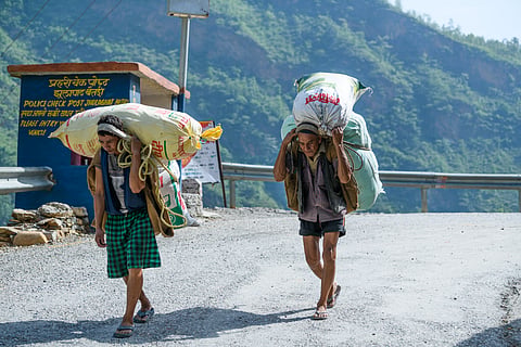 Porters carrying people's luggage crossing the India-Nepal Border in 2018. (This featured image was added online in 2024, and did not appear in the original print publication.)