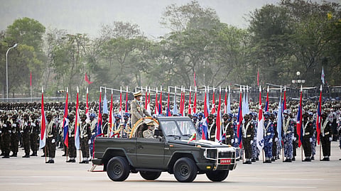 A military tank and rows of military on Armed Forces Day in Myanmar. They are all holding the Myanmar flag. 