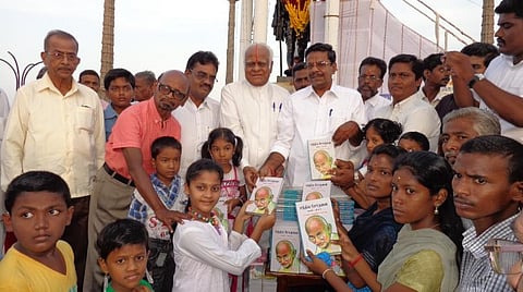காந்தி சிலை முன்பு சத்தியசோதனை நூலை இலவசமாக இளையோருக்கு விநியோகிக்கும் பேராசிரியர் சம்பத்குமார்