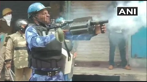 ராம்பூரில் இன்று போலீஸாருக்கும், போராட்டக்கார்களுக்கும் ஏற்பட்ட மோதலில் போலீஸார் ஒருவர் கண்ணீர் புகைக் குண்டை சுடும் காட்சி: படம் | ஏஎன்ஐ.