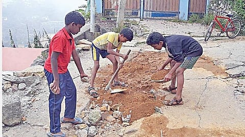 கொடைக்கானல் ஆனந்தகிரி பகுதியில் சேதமடைந்த சாலையை சீரமைக்கும் பள்ளி மாணவர்கள்.