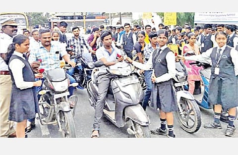 சாலை பாதுகாப்பு வார விழாவையொட்டி, திருப்பூரில் தலைக்கவசம் அணியாமல் வந்த வாகன ஓட்டிகளுக்கு பூ கொடுத்து அறிவுரை கூறிய பள்ளி மாணவிகள்.