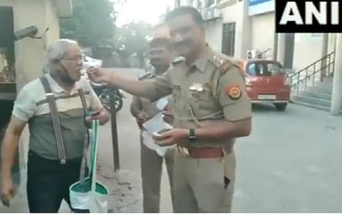 லாக் டவுன் ரோந்துப் பணிகளுக்கிடையிலும் ரத்த அழுத்தம் பாதித்த முதியவருக்கு லக்னோ போலீஸார் இனிப்பு ஊட்டி உதவும் காட்சி. | படம்: ஏஎன்ஐ.