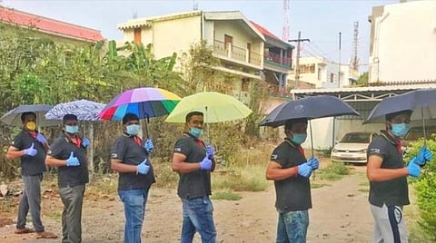 கையில் குடையுடன் தனி மனித விலகலைக் கடைப்பிடிக்கும் திருப்பூர் தன்னார்வலர்கள்.