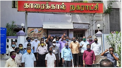 காரைக்கால் நகராட்சி அலுவலக வாயிலில் ஆர்ப்பாட்டத்தில் ஈடுபட்ட நகராட்சி ஊழியர்கள்.
