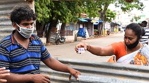 சாலையில் தடுப்பு அமைக்கும் பணியில் ஈடுபட்ட தொழிலாளிக்கு கசாயம் வழங்குகிறார் சுதா.