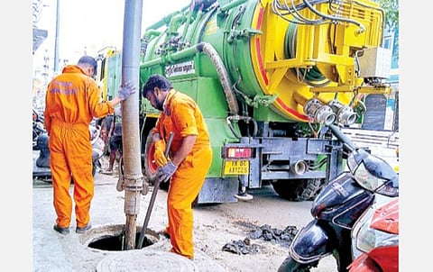 சென்னை பிராட்வே சாலையில் மழைநீர் வடிகாலில் படிந்துள்ள மண்ணை இயந்திரம் உறிஞ்ச ஏதுவாக கடப்பாறையால் பெயர்க்க முயலும் மாநகராட்சி இயந்திர பணியாளர்கள். படம்:  ச.கார்த்திகேயன்