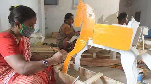 மரப்பொம்மைக்கு வர்ணம் பூசும் பணியில் ஈடுபட்டுள்ள மகளிர் குழுவினர்.