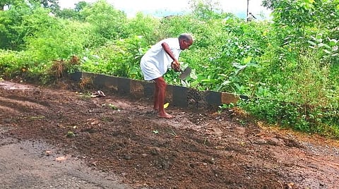 பாகூர் மாஞ்சோலை சாலையில் உள்ள பள்ளங்களை மணல் கொண்டு மூடும் முதியவர் புருஷோத்தமன்.