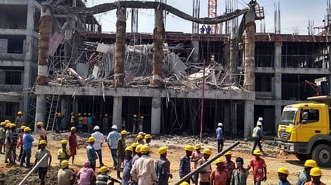 இடிந்து விழுந்த கட்டிடத்தை அதிர்ச்சியுடன் பார்க்கும் தொழிலாளர்கள்.