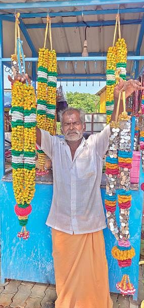 காசு மாலை, சாக்லெட் மாலைகளுடன் வியாபாரி கருப்பசாமி. படம்: த.அசோக் குமார்