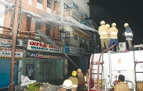 மதுரை விளக்குத்தூண் அருகே உள்ள ஜவுளிக் கடையில் பற்றி எரியும் தீயை தண்ணீர் பீய்ச்சி அடித்து அணைக்கும் பணியில் ஈடுபட்ட தீயணைப்பு வீரர்கள். படம்: எஸ்.கிருஷ்ணமூர்த்தி.