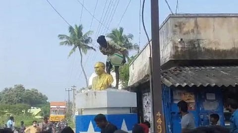 சிலையைத் தண்ணீர் ஊற்றி சுத்தம் செய்யும் இளைஞர்.