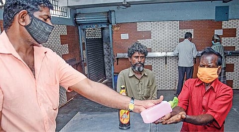 சென்னை திருவல்லிக்கேணியில் உள்ள டாஸ்மாக் பாருக்கு வந்த நபர்கள் உடல் வெப்பநிலை பரிசோதனை செய்த பிறகு கைகளை சுத்தப்படுத்த சானிடைசர் கொடுக்கப்படுகிறது. படம்: பு.க.பிரவீன்