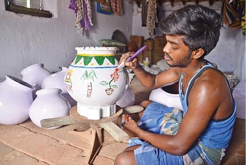 மண் பாண்டங்களுக்கு வர்ணம்  தீட்டும் முதுகலை  மாணவர் க. அருணாசலம்