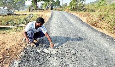 தொங்குமலை-நம்மியம்பட்டு இடையே தரமற்ற தார்ச் சாலை அமைக்கப்பட்டுள்ளதாக சுட்டிக்காட்டும் இளைஞர். படம்: வி.எம்.மணிநாதன்.